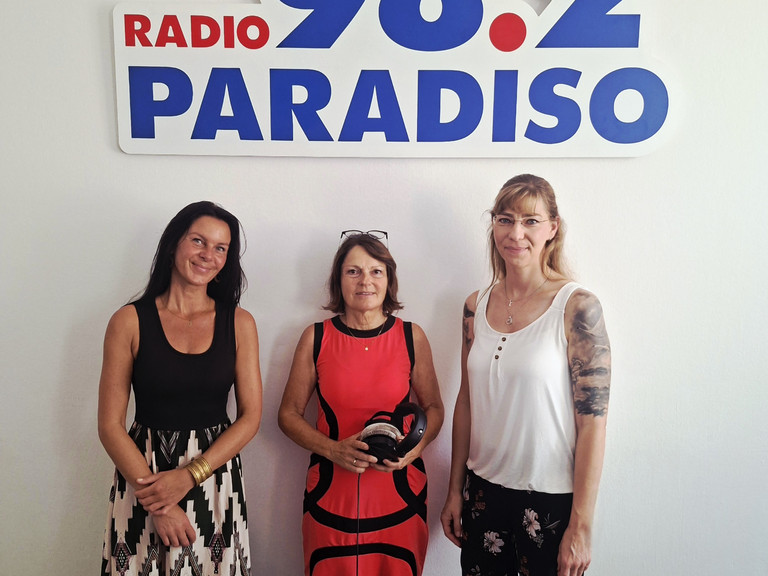 Kunsttherapeutin Sabrina Müller, Radiomoderatorin Julia Nogli und Pflegedienstleitung Stefanie Micklitza stehen unter dem Logo von Radio Paradiso bei der Sendung über die Ermöglichung wertvoller und erfüllter Momente am Lebensende im Diakonie Hospiz Woltersdorf. Kunsttherapeutin Sabrina Müller, Radiomoderatorin Julia Nogli und Pflegedienstleitung Stefanie Micklitza stehen unter dem Logo von Radio Paradiso bei der Sendung über die Ermöglichung wertvoller und erfüllter Momente am Lebensende im Diakonie Hospiz Woltersdorf.