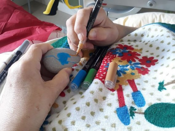 Gast bemalt Steine - Kreative Auseinandersetzung mit Erlebnissen in Kunsttherapie - Diakonie Hospiz Woltersdorf